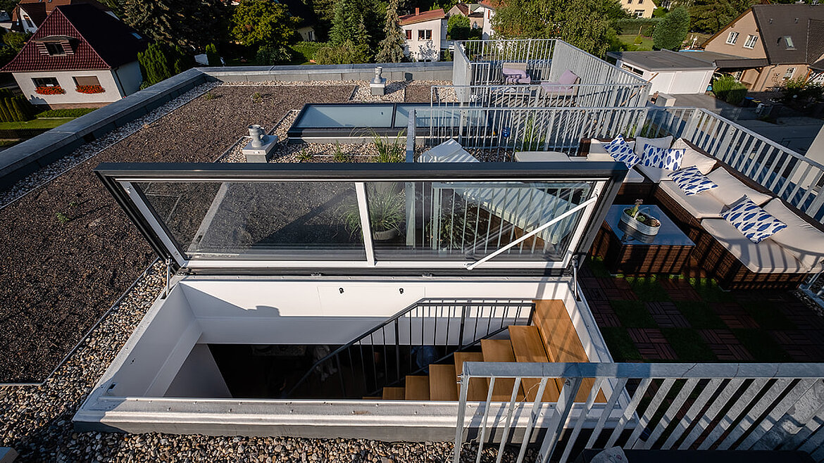 Moderne Dachterrasse mit integriertem Glasdach und Sitzbereichen in urbaner Umgebung