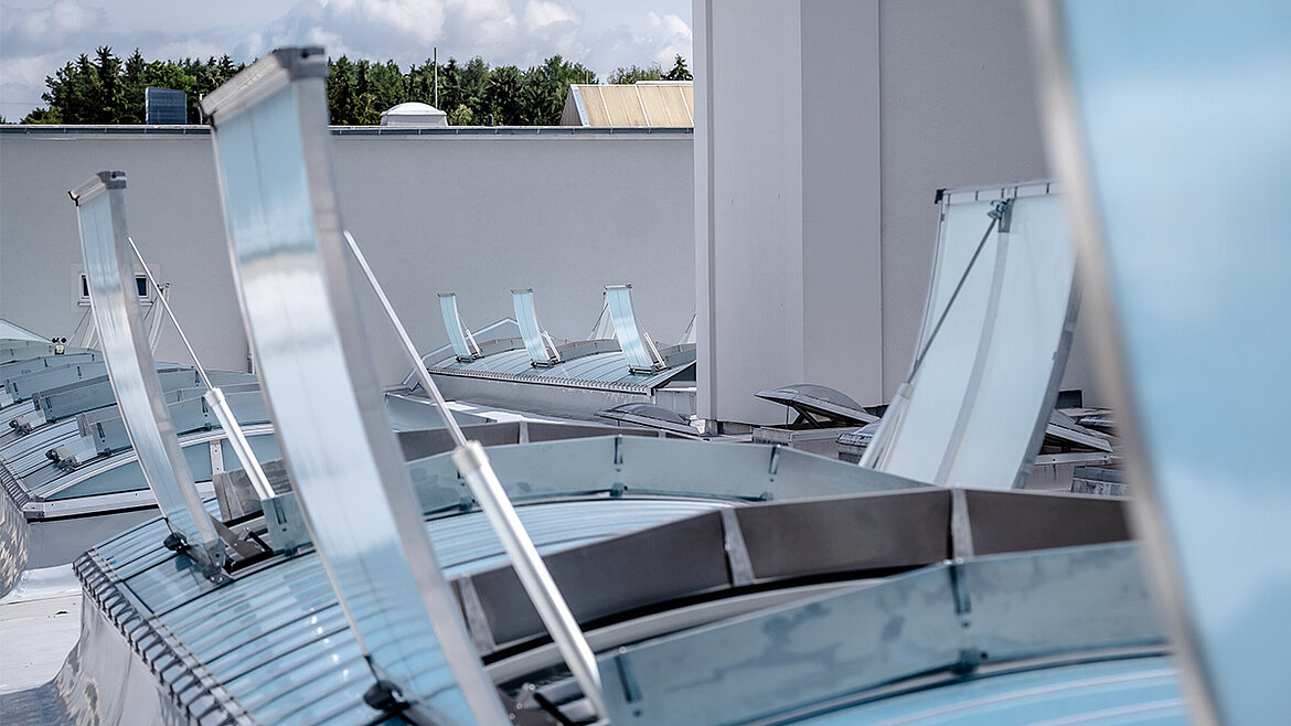 Mehrere geöffnete Lichtbänder auf dem Flachdach eines modernen Industriegebäudes mit Aluminiumrahmen