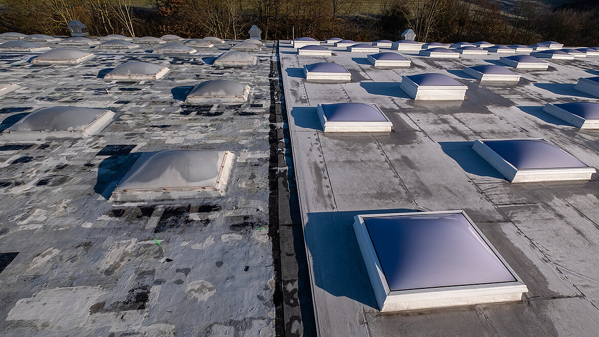 Flachdach mit mehreren Lichtkuppeln und Lüftungsöffnungen unter blauem Himmel