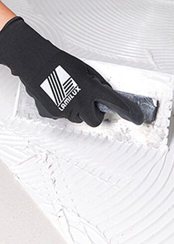 Hand mit Lamilux-Handschuhen glättet weiße Substanz.