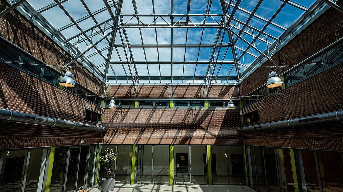 Industriehalle mit großflächigem Glasdach und historischer Stahlkonstruktion im Innenraum