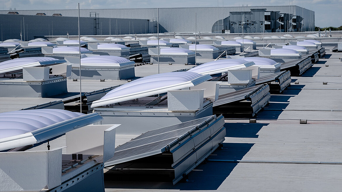Flachdach mit Lichtkuppeln und Solarpanelen auf Industriegebäude