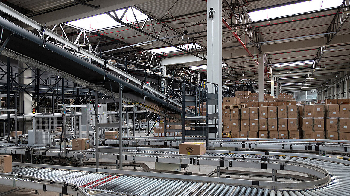 Blick in eine Produktionshalle mit Förderband. Darüber sorgen Lichtbänder für Tageslichteinfall
