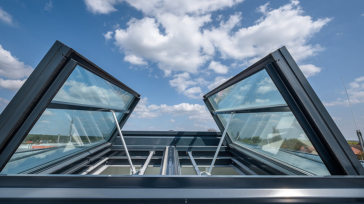 Geöffnetes Dachfenster mit Aluminiumrahmen und blauem Himmel