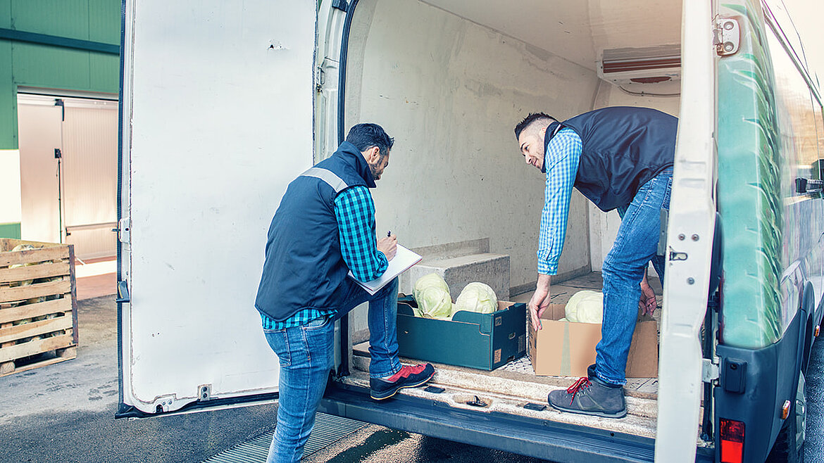 Männer beladen Lebensmitteltransporter Zwei Männer beladen einen Transporter mit Gemüse