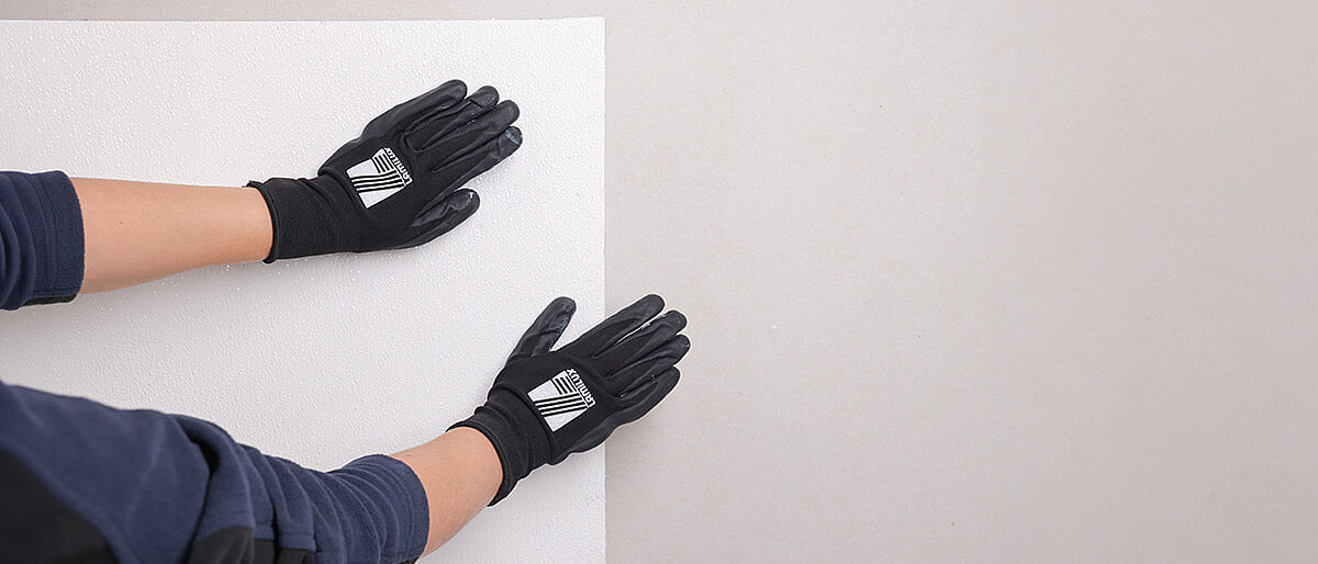 Person drückt eine weiße Platte gegen eine Wand