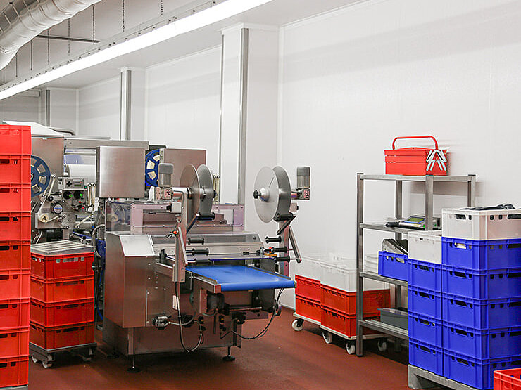 Innenansicht einer Produktionsanlage mit Maschinen und gestapelten Kunststoffkisten