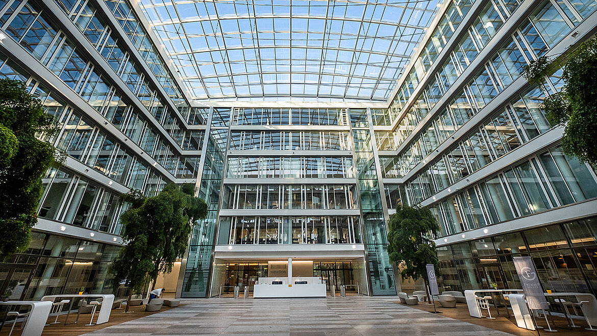 Mehrgeschossiges Atrium mit großflächigem Glasdach und begrünten Innenbereichen