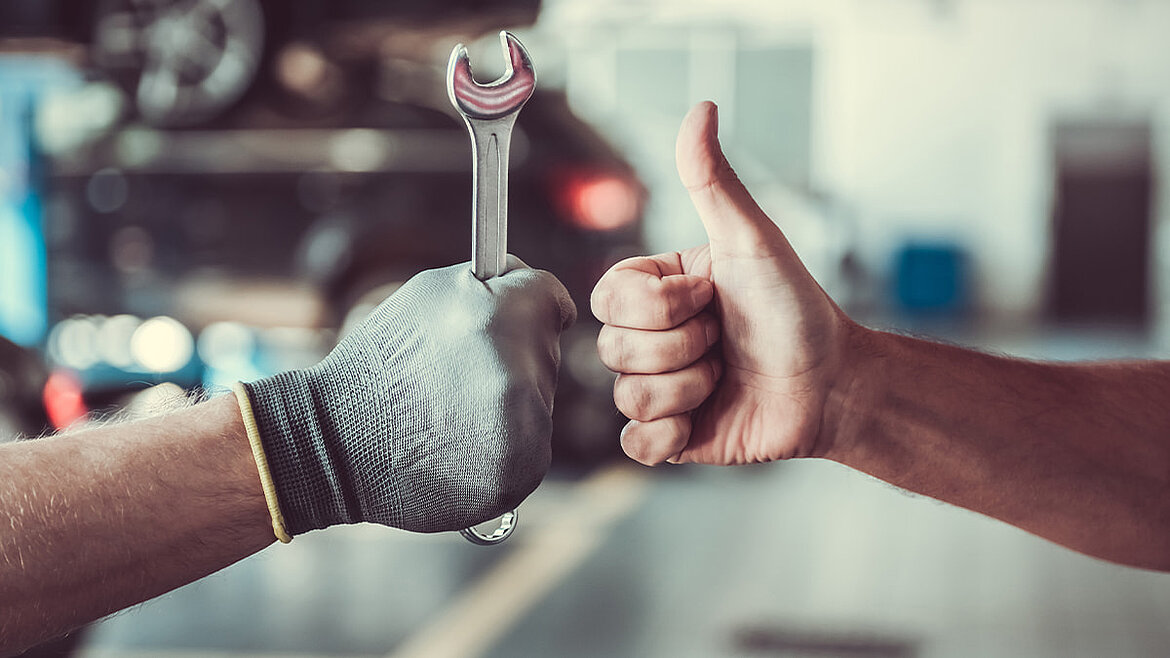 Zwei Hände mit Daumen hoch, eine mit Arbeitshandschuh, symbolisieren professionellen Vor-Ort-Service