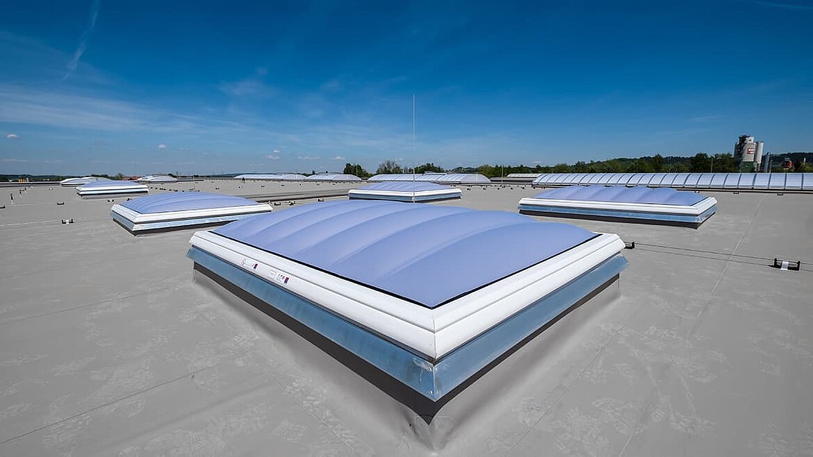 Lamilux Flachdach mit mehreren Lichtkuppeln unter blauem Himmel.