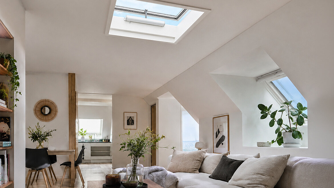 Helles Wohnzimmer mit weißem Sofa, Holztisch und Pflanzen 