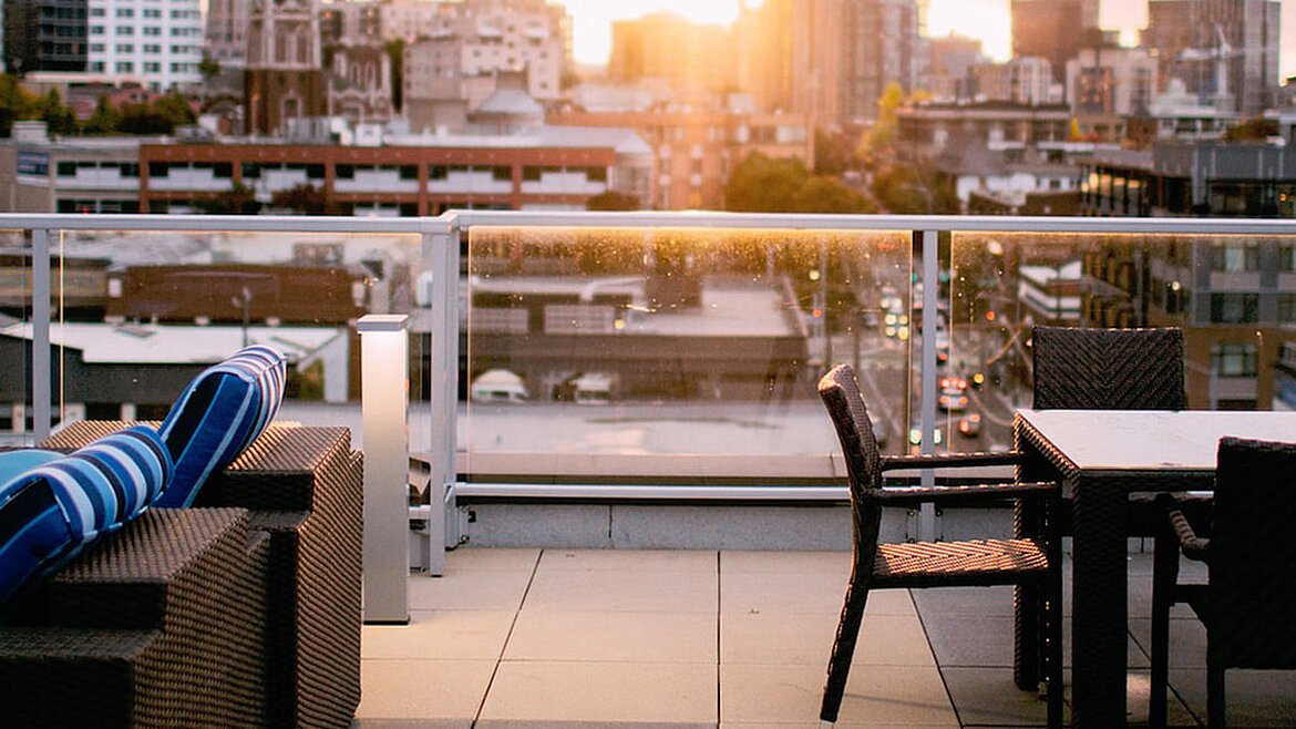 Stilvolle Dachterrasse mit Sitzmöbeln und Blick auf die Stadt im Sonnenuntergang.