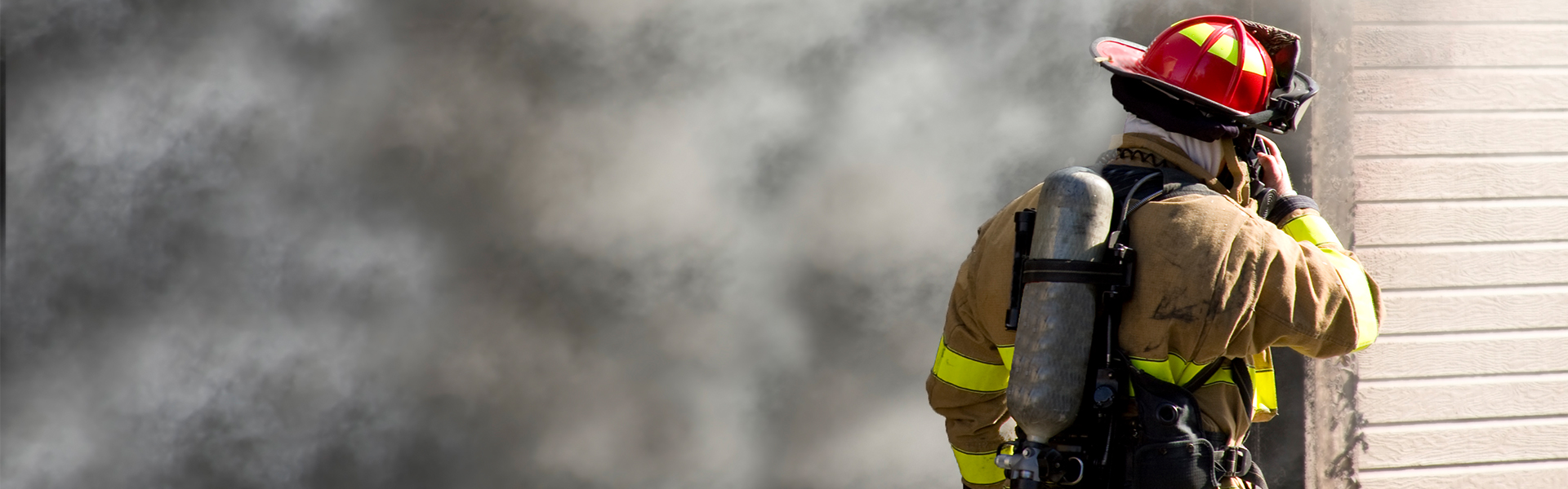 Feuerwehrmann steht vor brennenden Haus